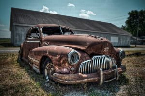 Rusty 1942 Buick automobile with front damage and broken headlights, no glass